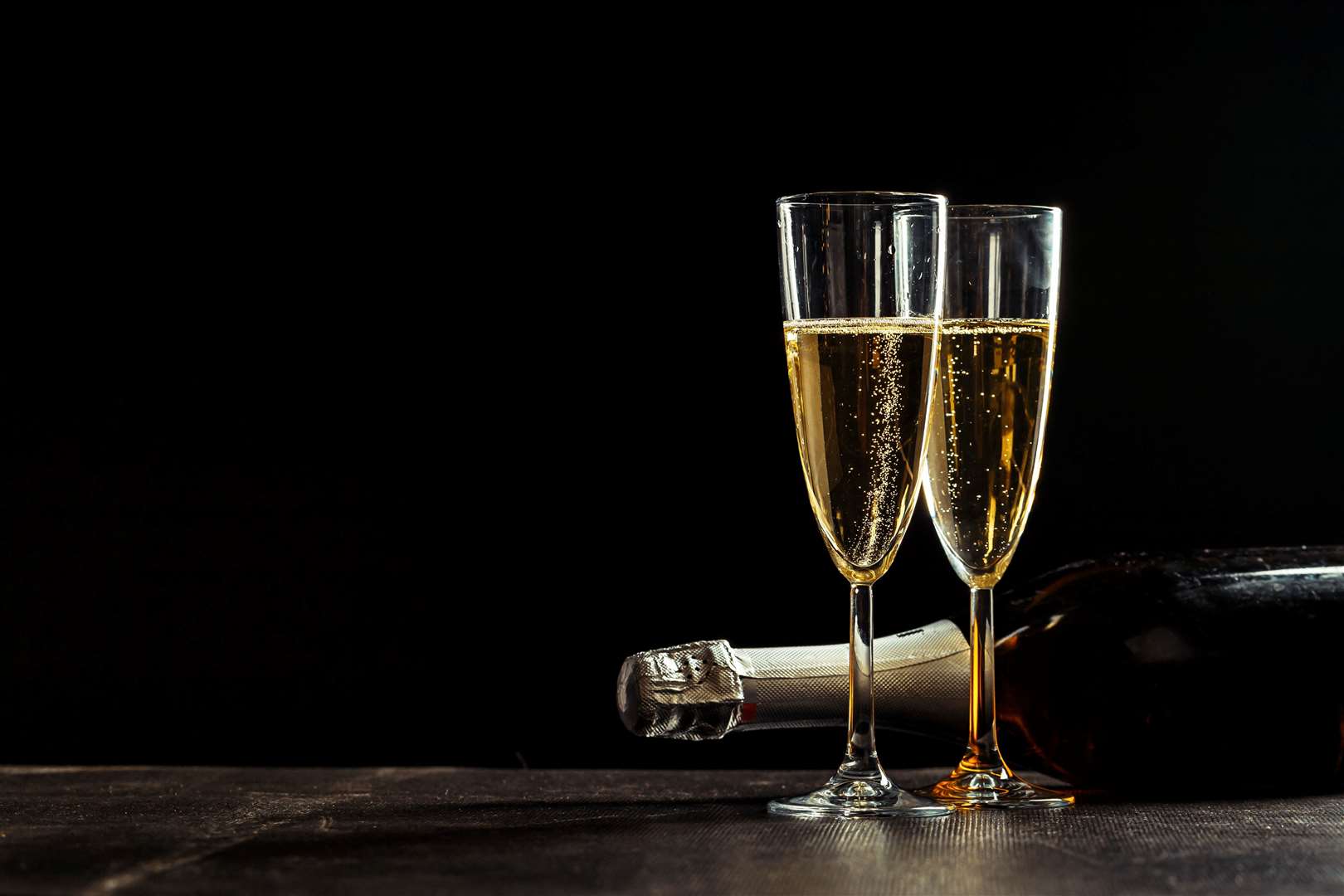 Bottle of champagne and glasses over dark background
